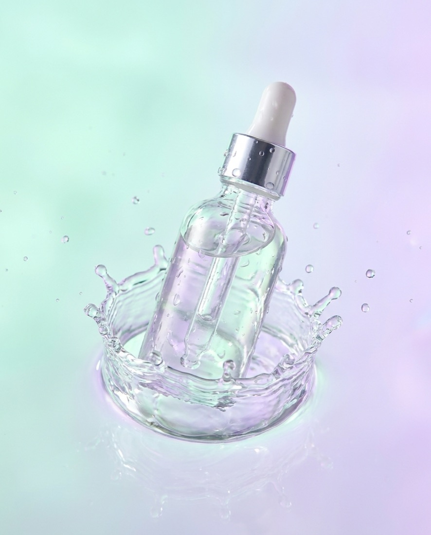 Skincare campaign visual — serum bottle in a water splash